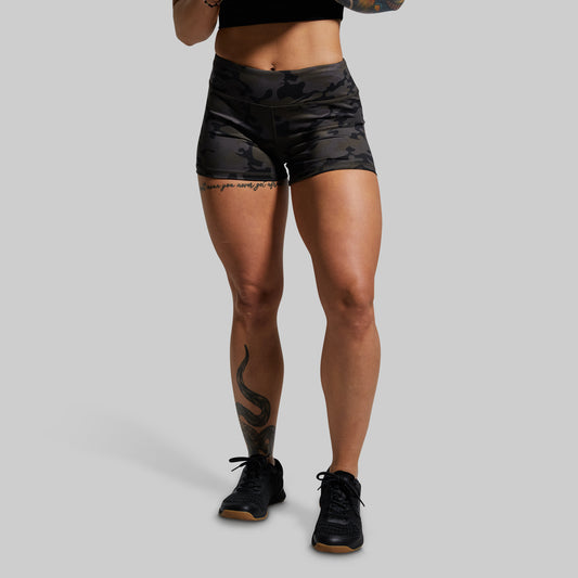 Person wearing black camouflage shorts on a gray background