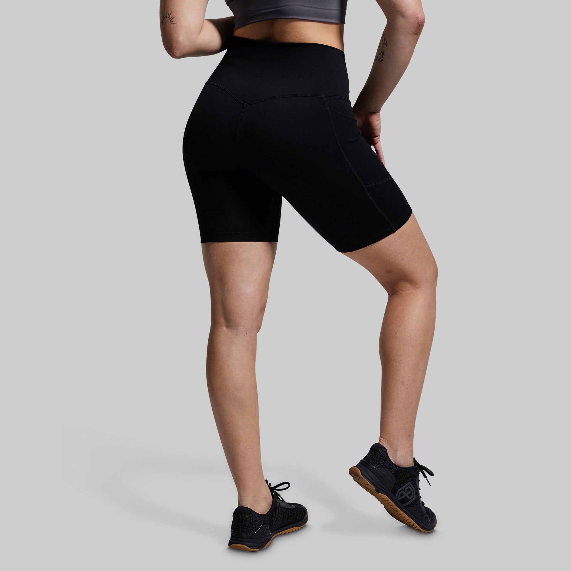 Person wearing black athletic shorts on a light gray background
