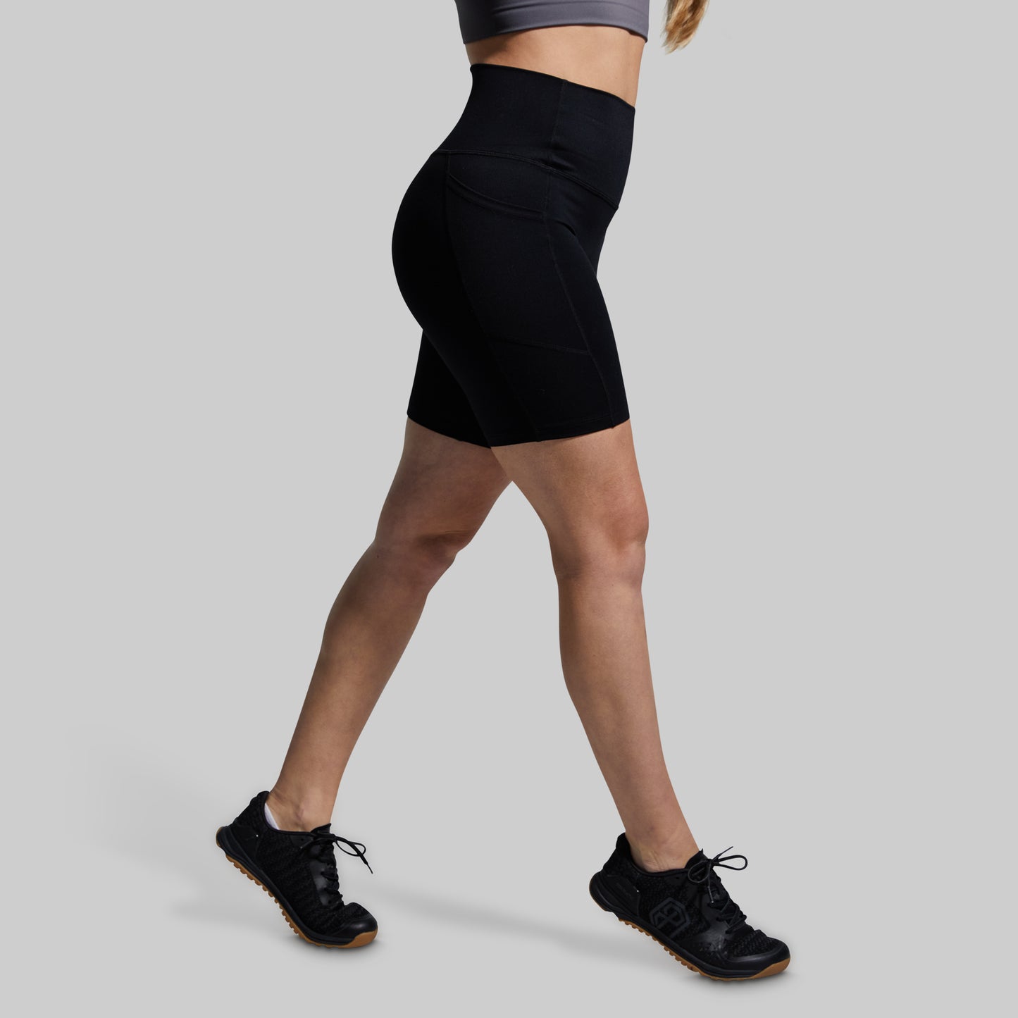 Person wearing black athletic shorts on a gray background