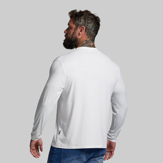 Man wearing a white long-sleeve shirt and blue jeans on a gray background