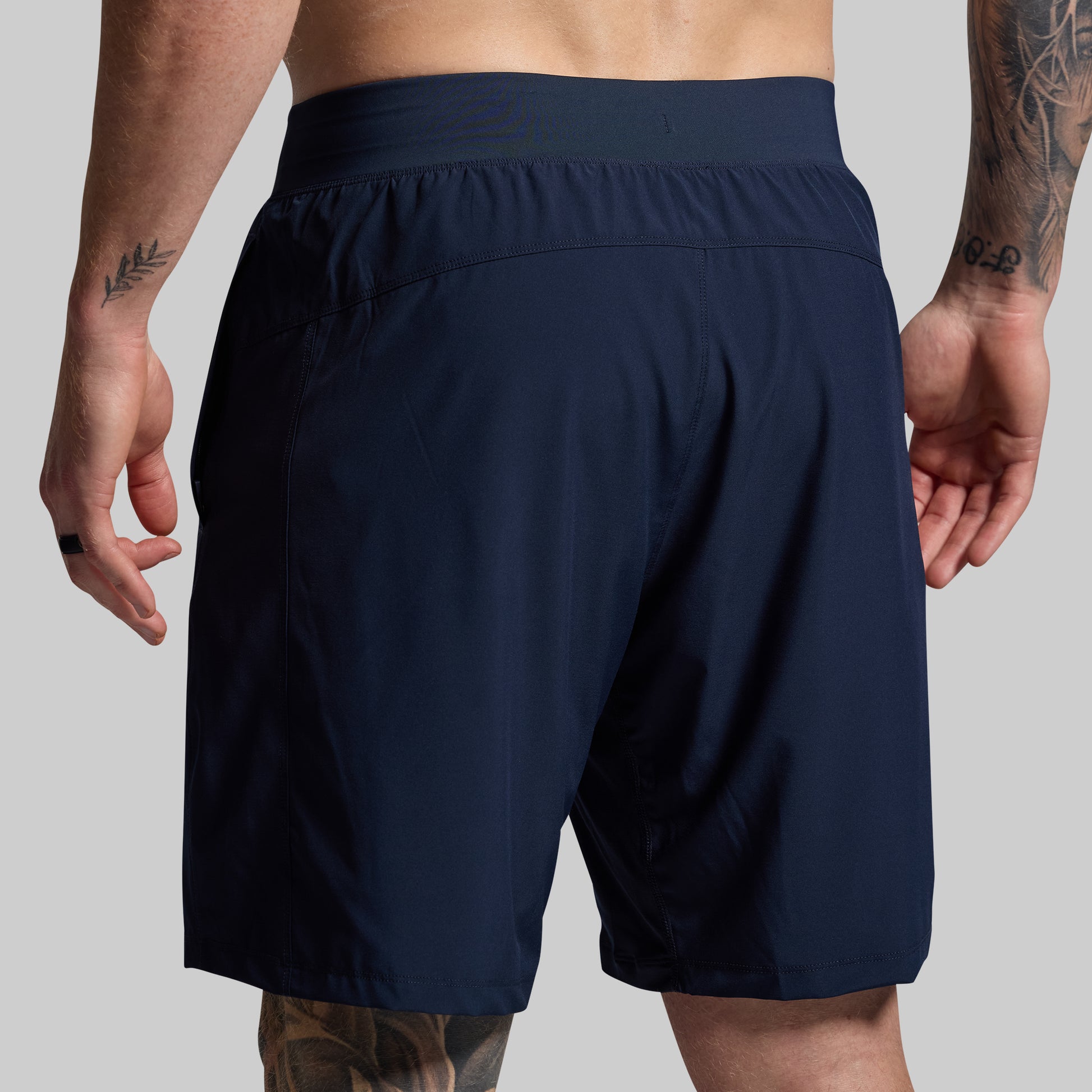 Navy blue shorts worn by a person on a gray background