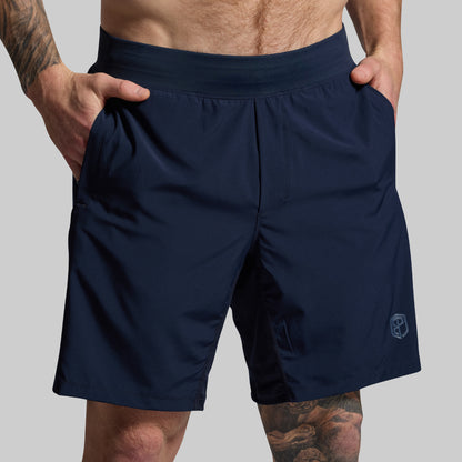 Navy blue shorts worn by a person on a gray background