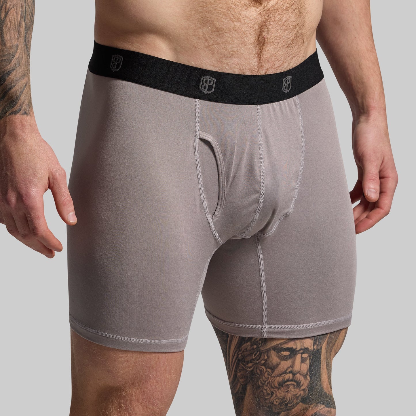 Man wearing gray boxer briefs on a plain background