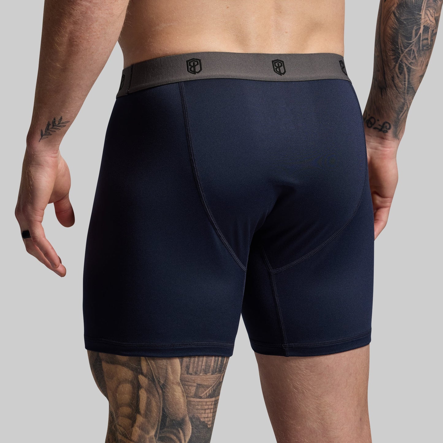 Man wearing navy boxer briefs on a gray background