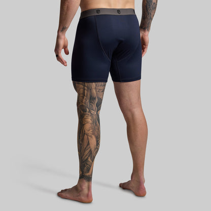 Man wearing navy boxer briefs on a gray background