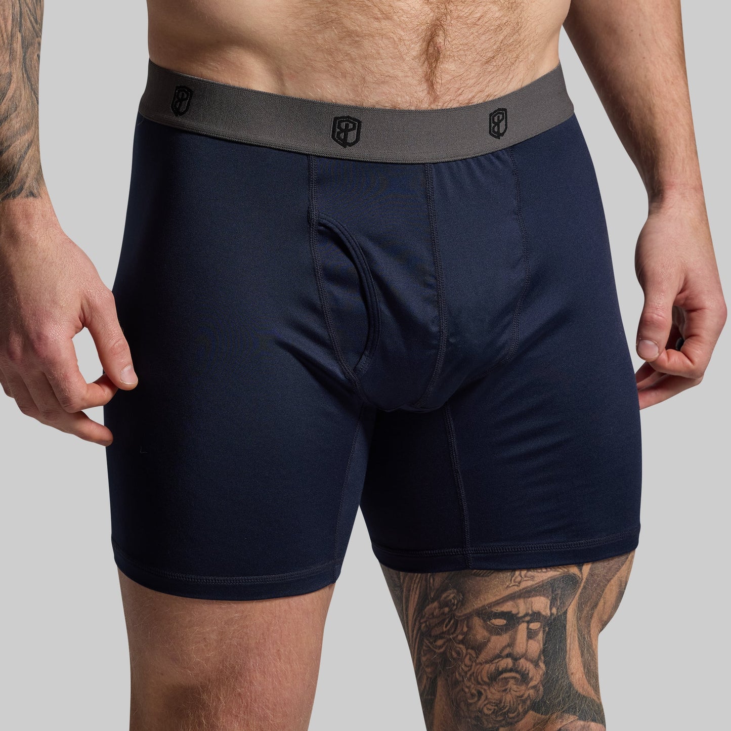 Man wearing navy boxer briefs on a gray background