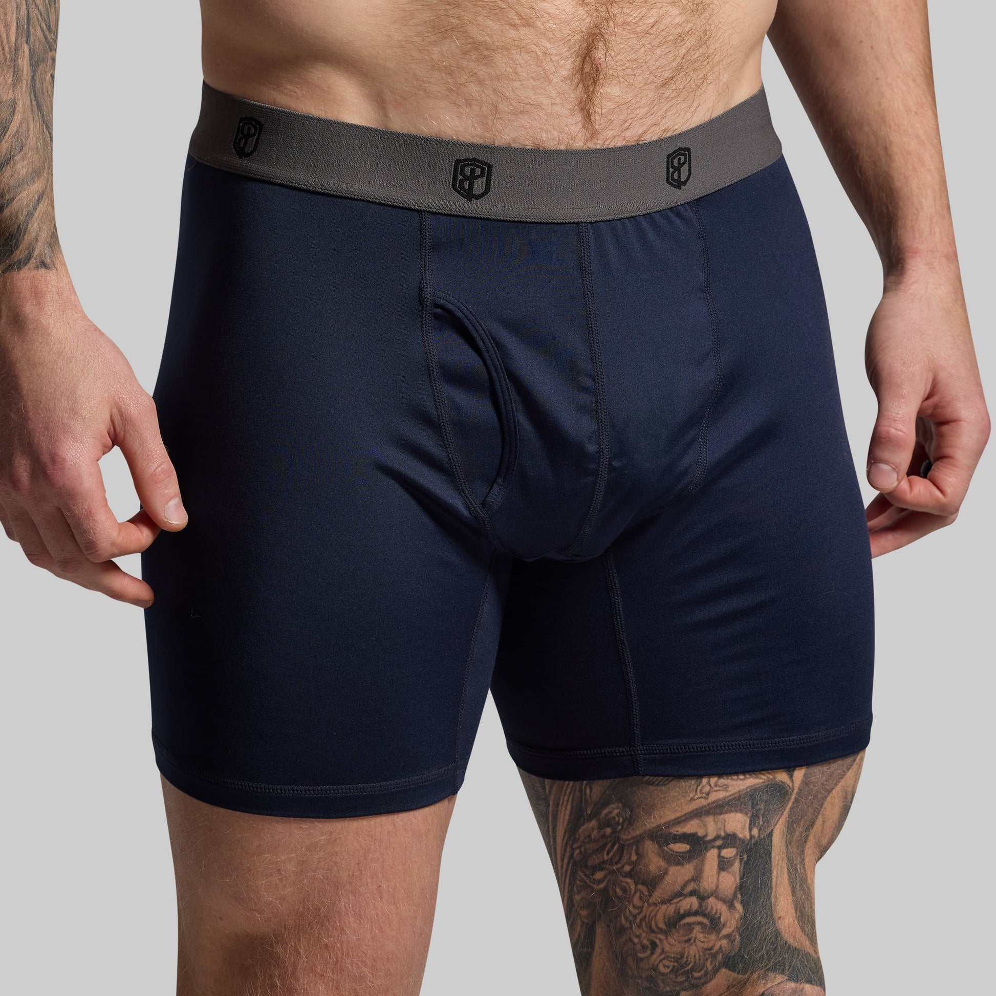 Man wearing navy boxer briefs on a gray background