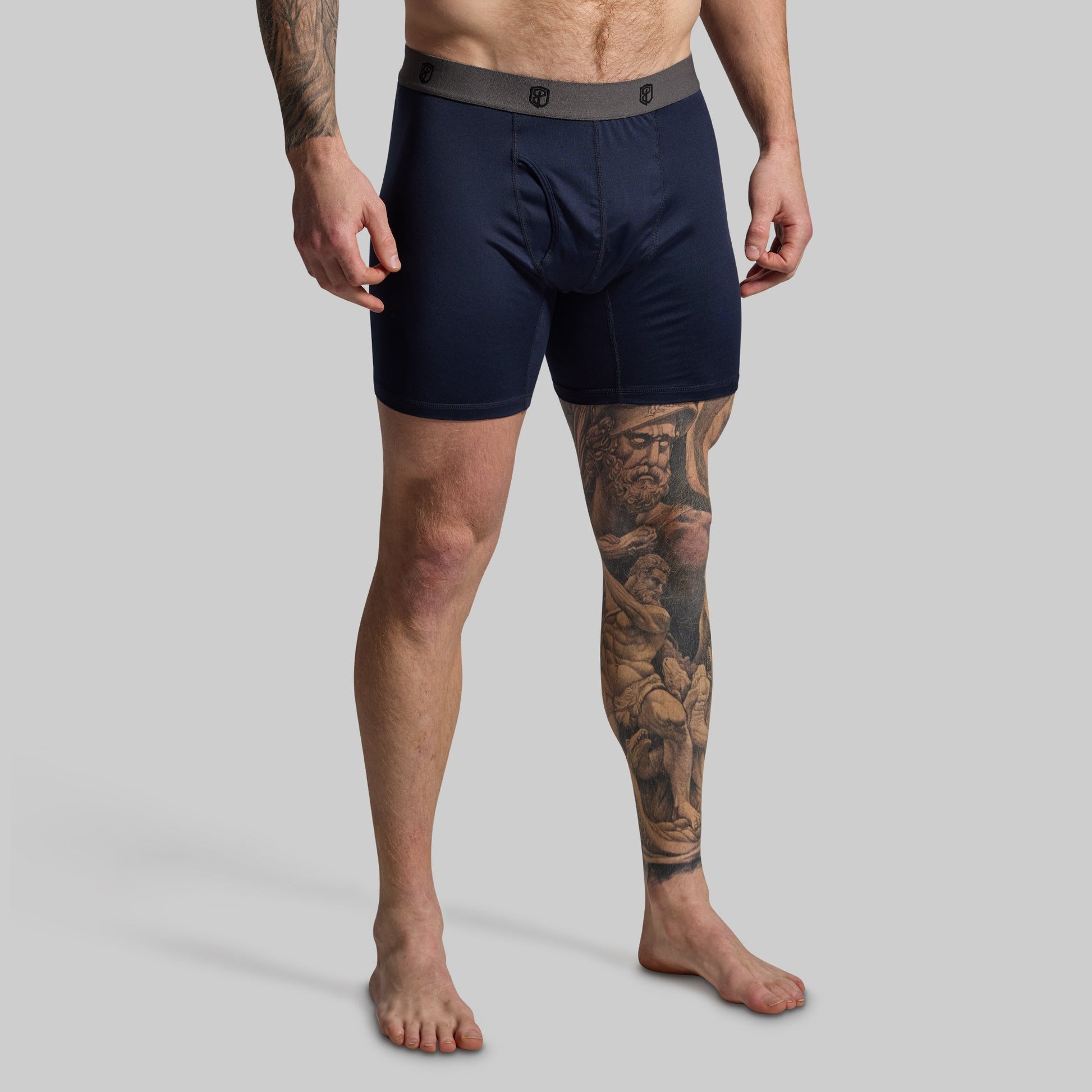Man wearing navy boxer briefs on a gray background