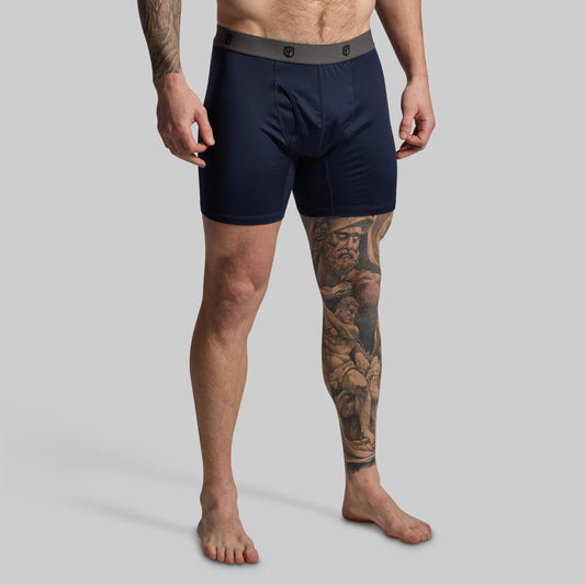Man wearing navy boxer briefs on a gray background