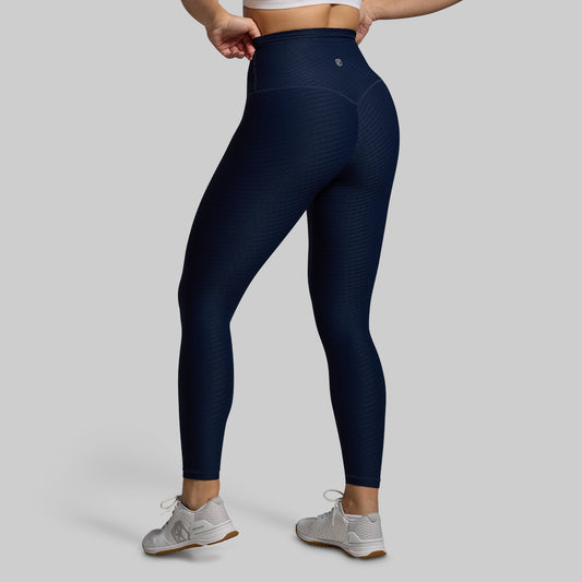 Navy blue leggings worn by a person on a gray background