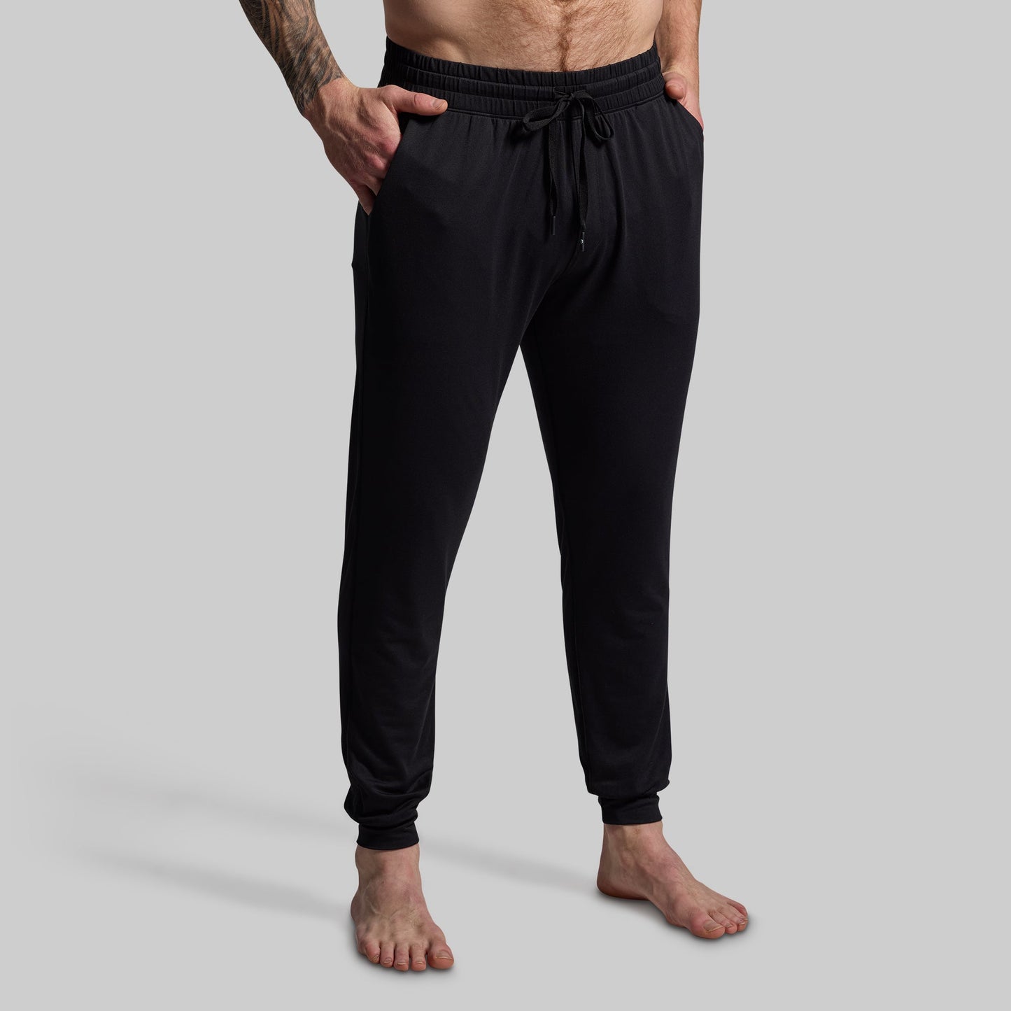 Person wearing black jogger pants on a gray background