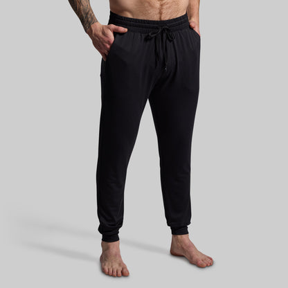 Person wearing black jogger pants on a gray background