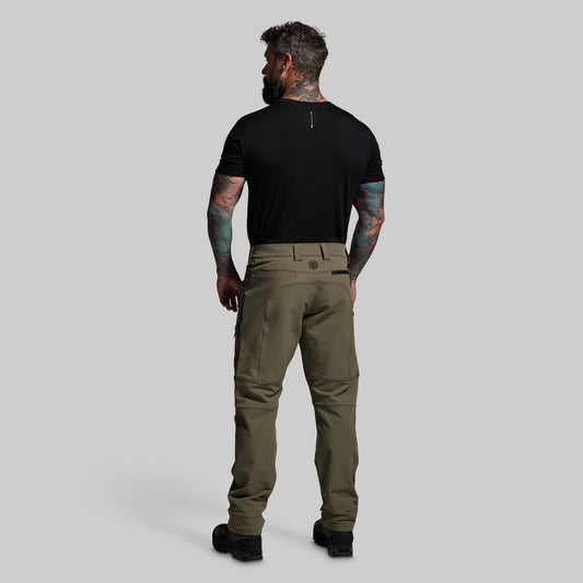 Man wearing olive green pants and a black t-shirt on a gray background