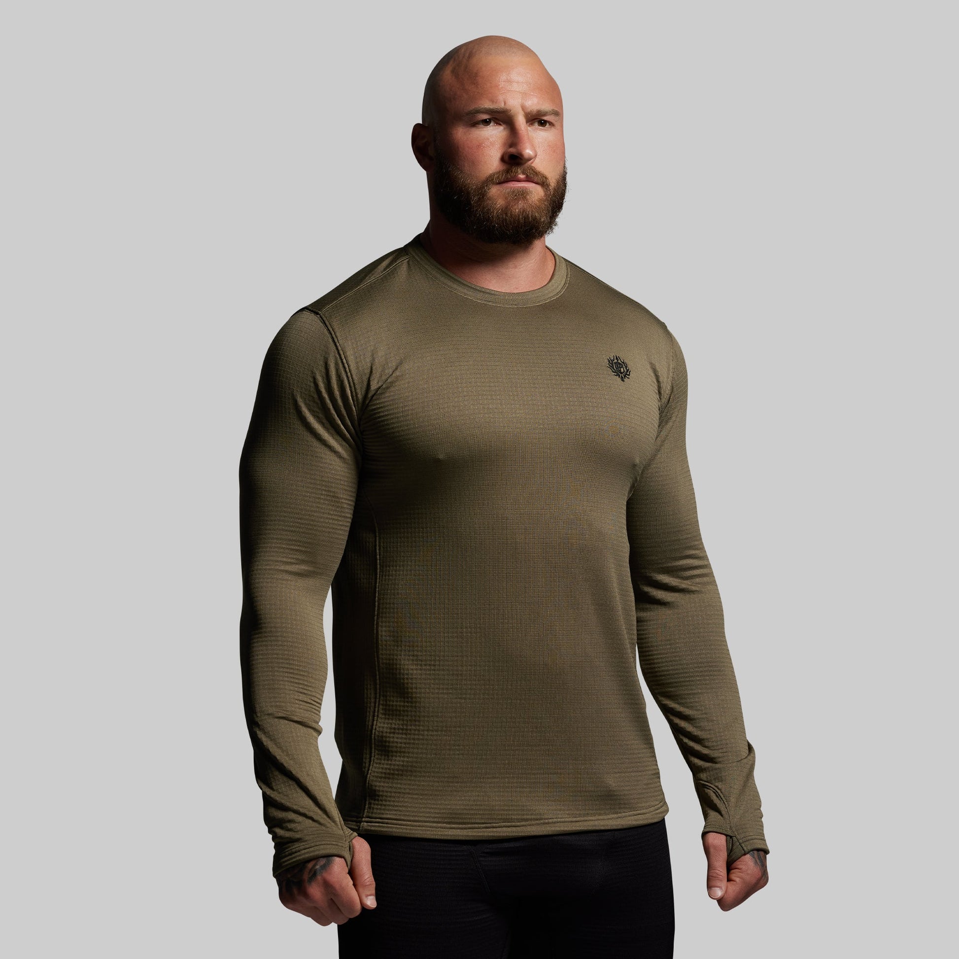 Man wearing a green long-sleeve shirt against a gray background