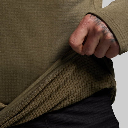 Person wearing a green base layer with a close-up of the inner lining on a gray background