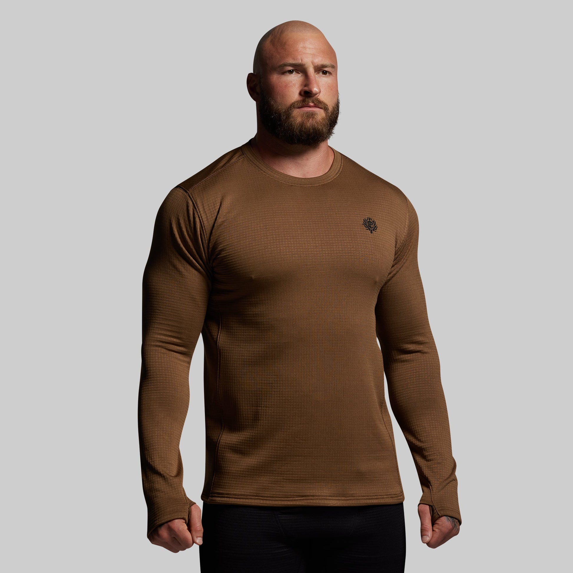 Man wearing a brown long-sleeve shirt against a gray background
