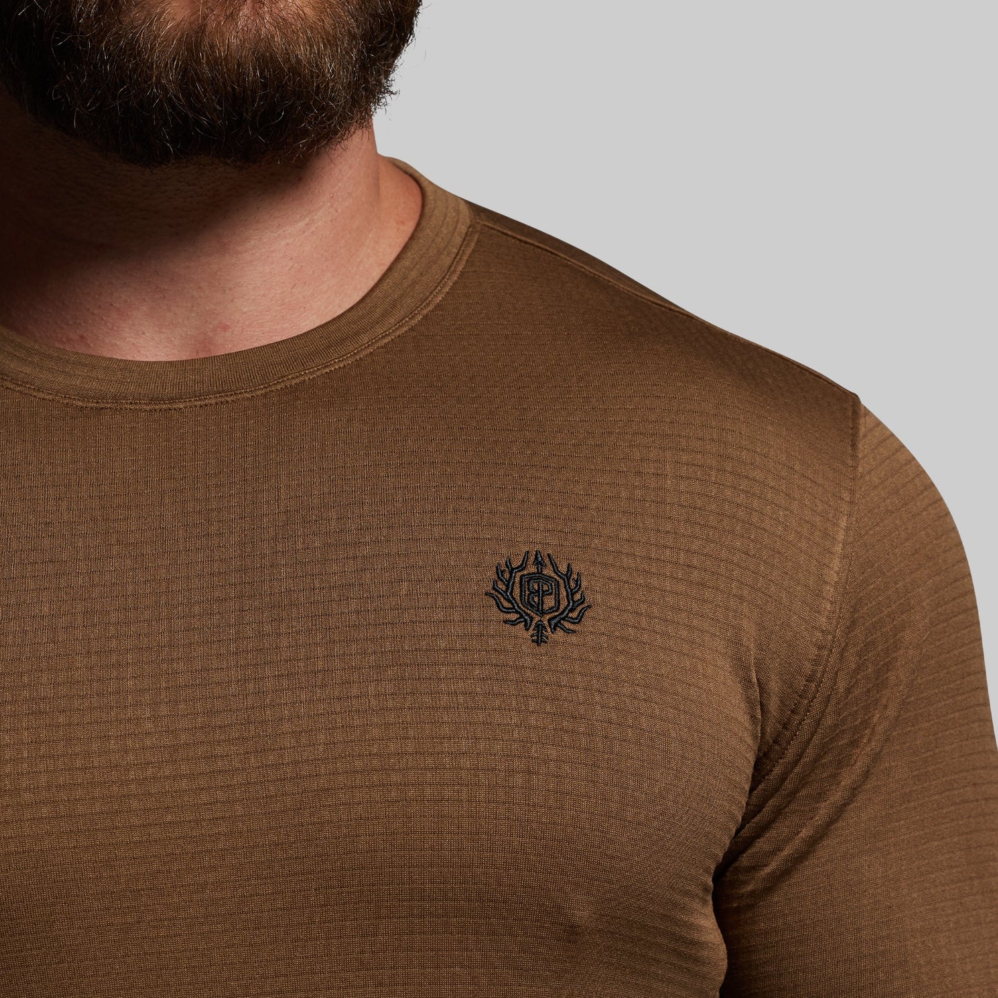 Brown long-sleeve shirt with a small logo on a gray background