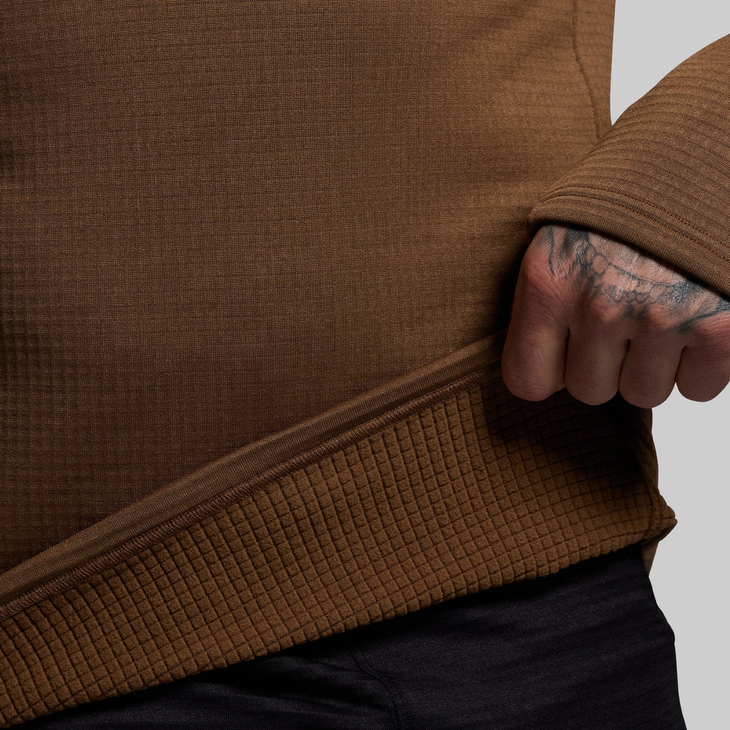 Close-up of a person wearing a brown textured base layer with a neutral background