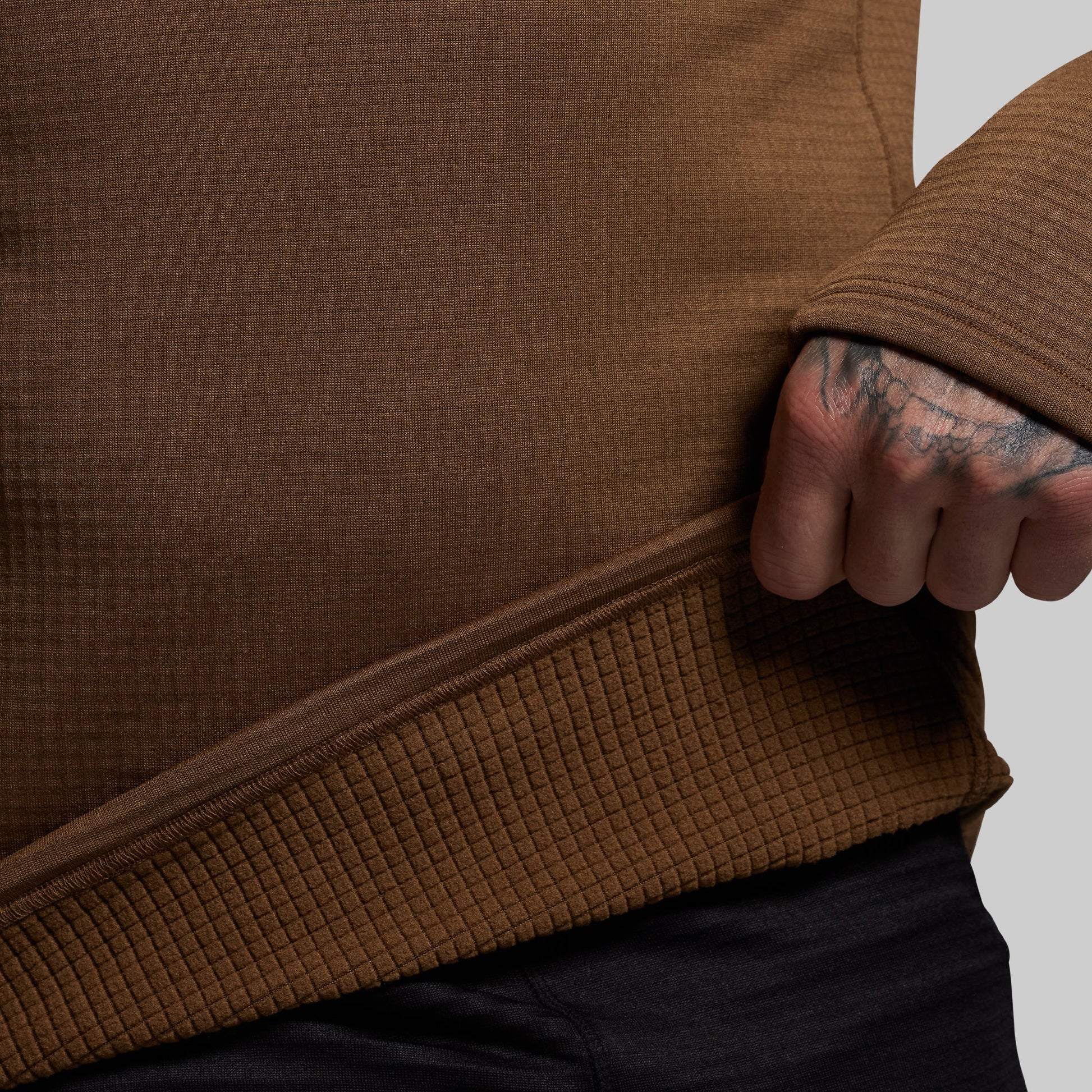 Close-up of a person wearing a brown textured base layer with a neutral background