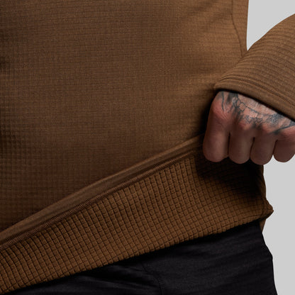 Close-up of a person wearing a brown textured base layer with a neutral background