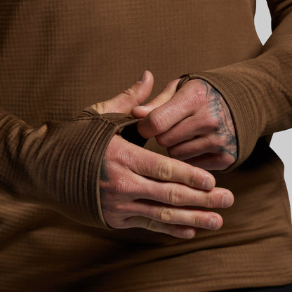 Close-up of a person wearing a brown long-sleeve shirt with tattooed hands.