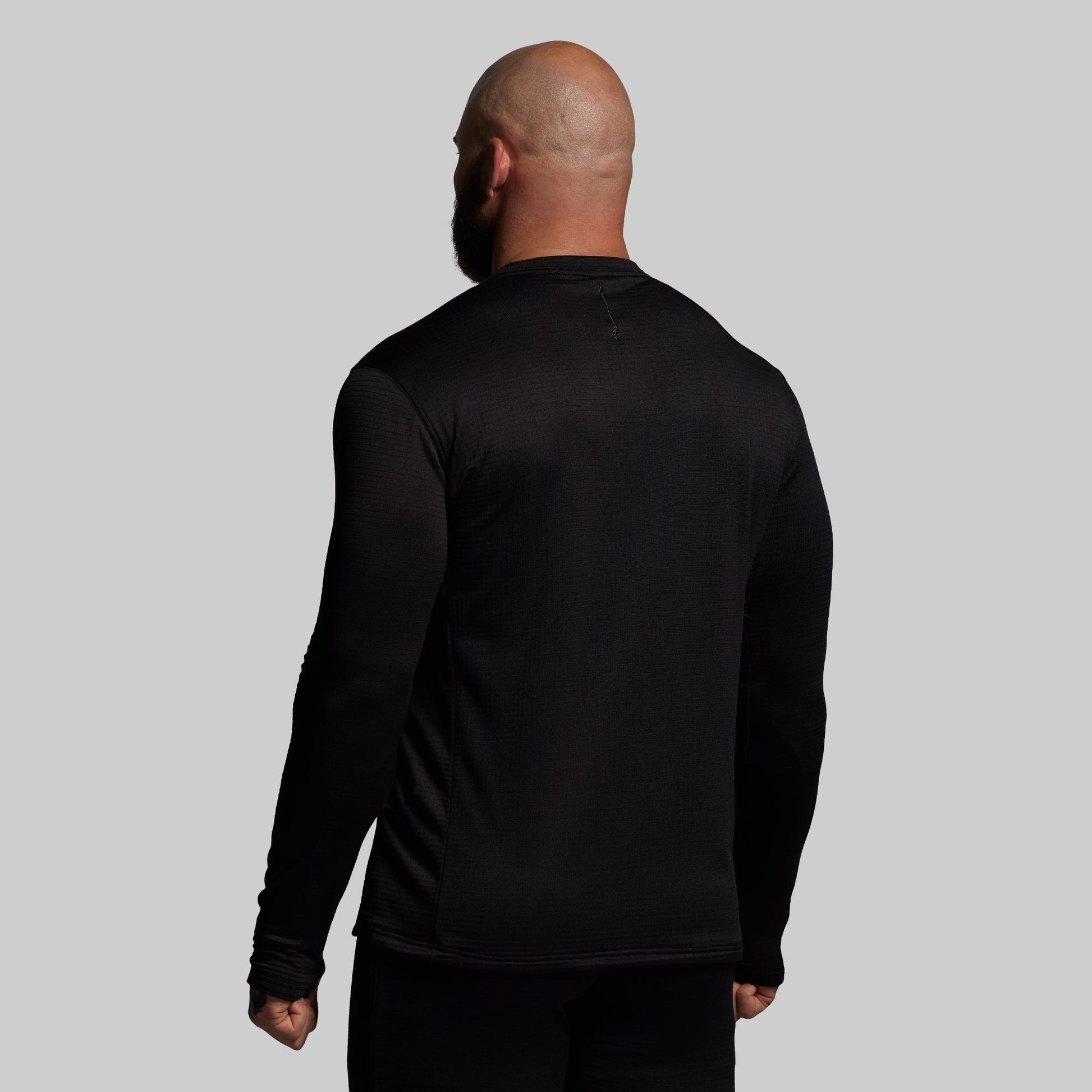 Person wearing a black long-sleeve shirt against a gray background