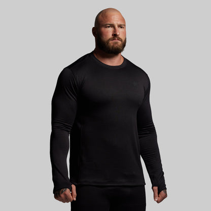 Man wearing a black long-sleeve shirt against a gray background