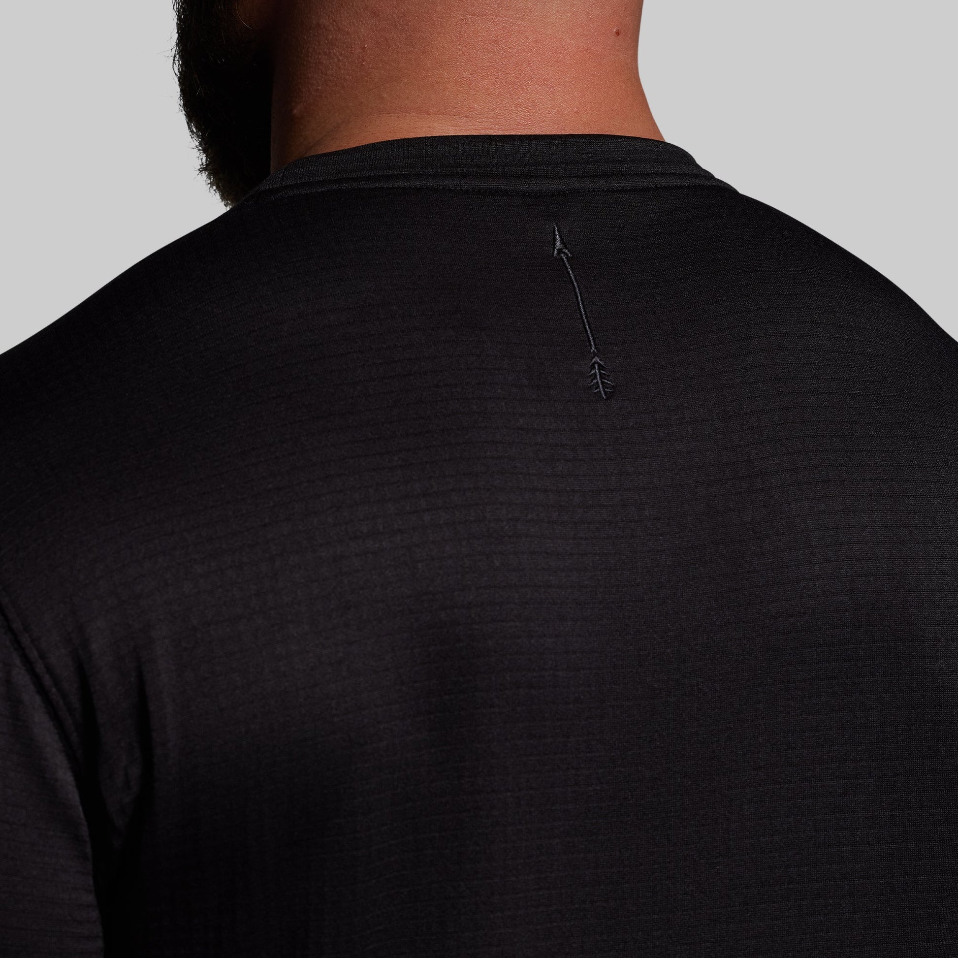Black long sleeve base layer worn by a person on a gray background