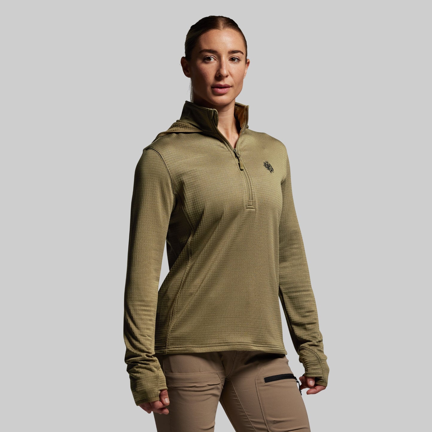 Person wearing a green pullover with a logo on a gray background