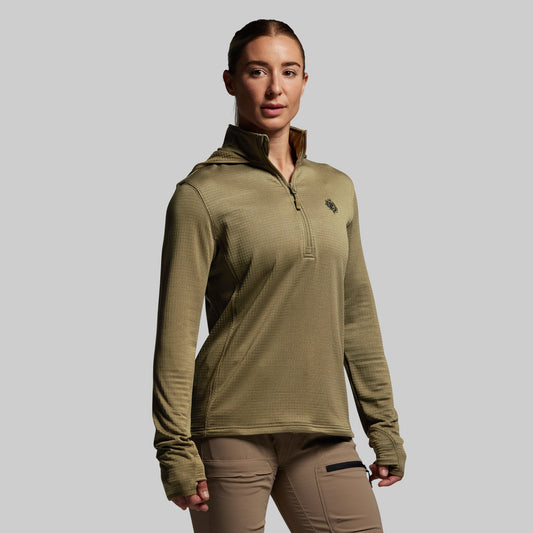 Person wearing a green pullover with a logo on a gray background
