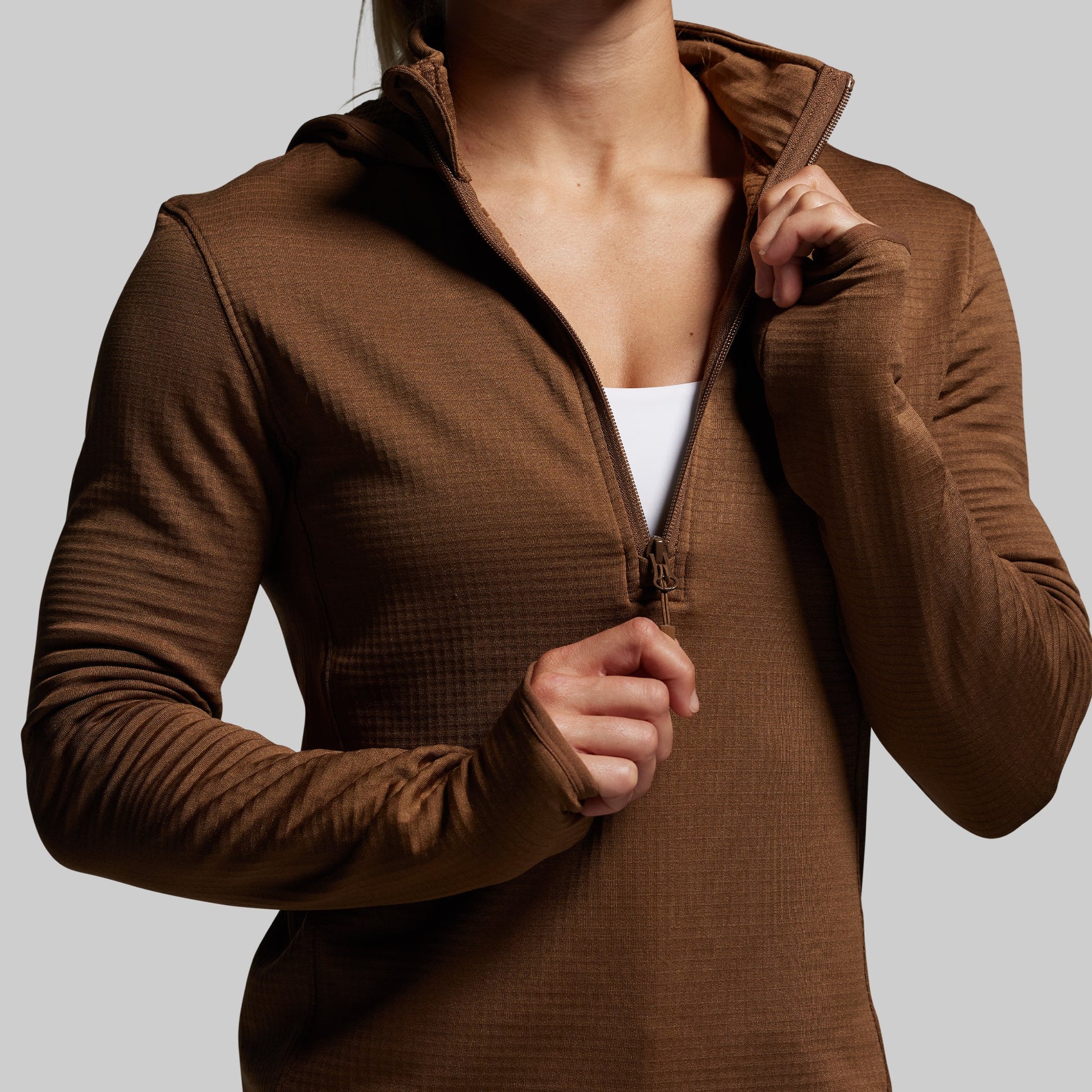 Brown half zip hoodie worn by a person on a plain background