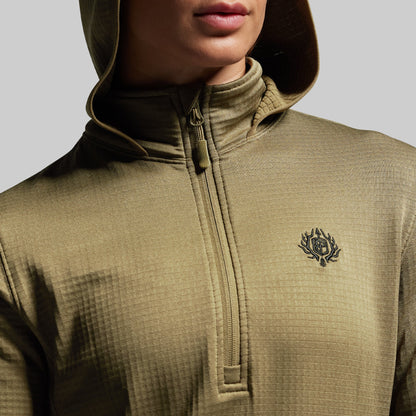 Close-up of a person wearing a green hoodie with a brand logo on a gray background