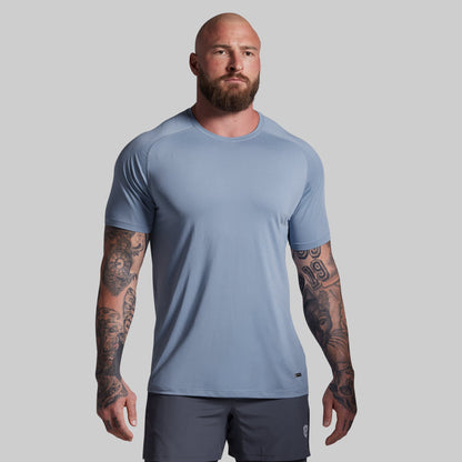 Man wearing a light blue athletic shirt and dark shorts on a gray background