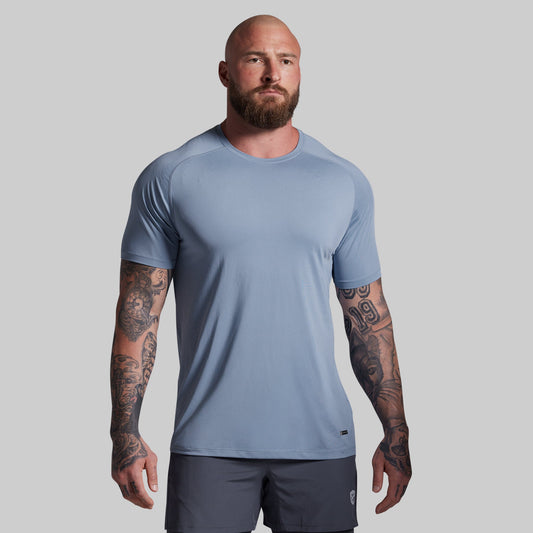 Man wearing a light blue athletic shirt and dark shorts on a gray background