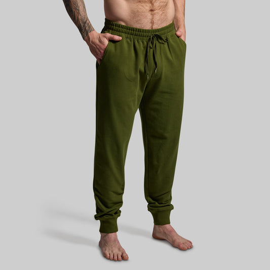 Green sweatpants worn by a person on a gray background