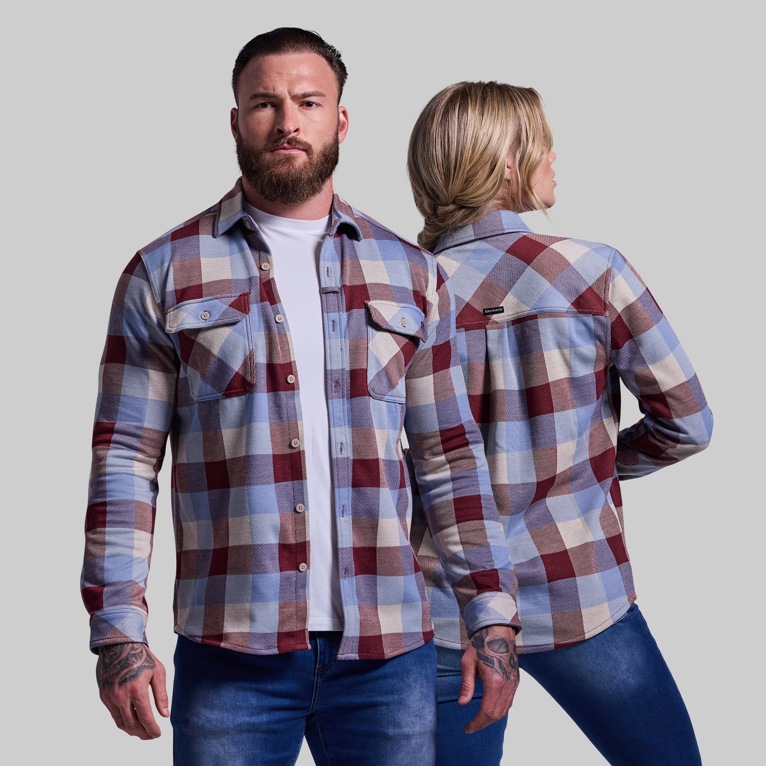 Man and woman wearing plaid shirts against a plain background