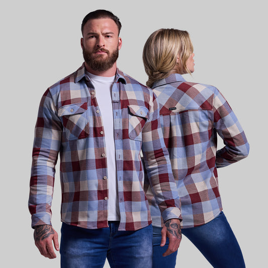 Man and woman wearing plaid shirts against a plain background