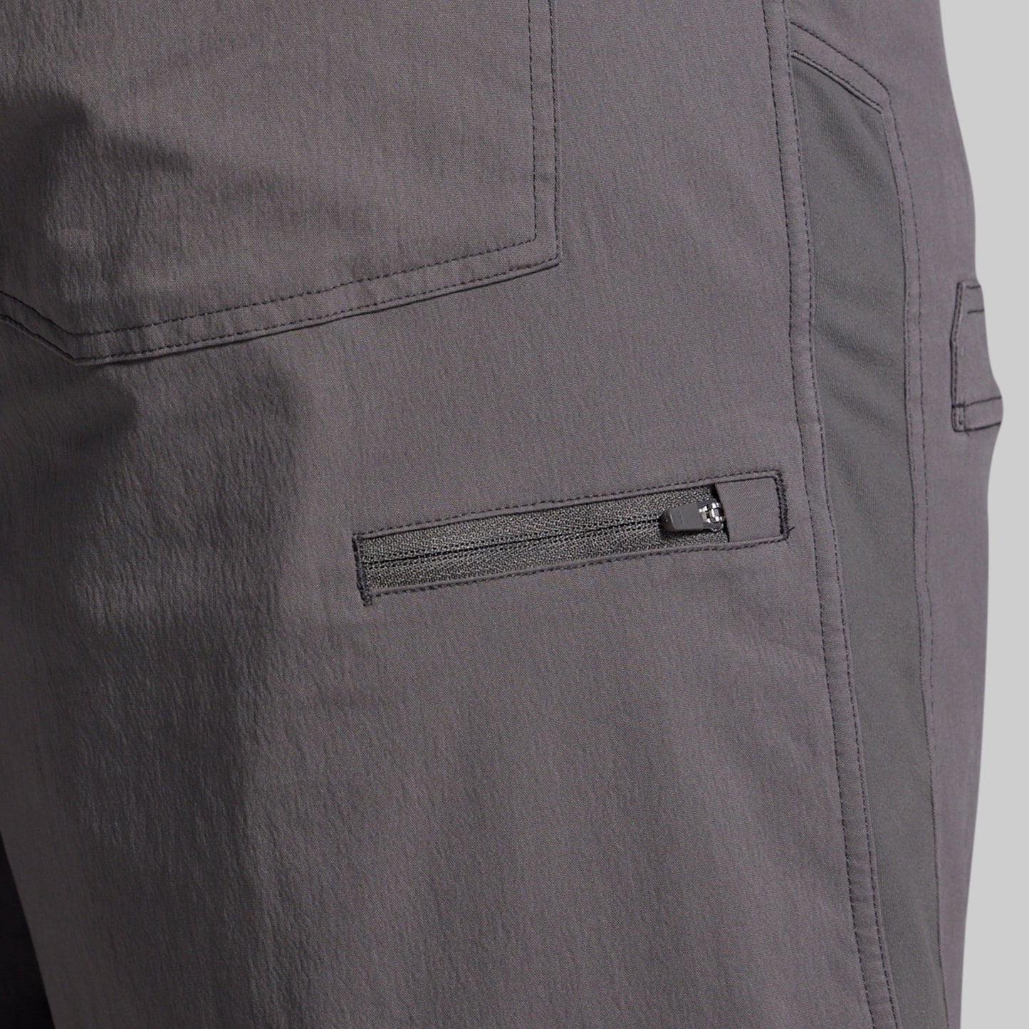 Close-up of gray shorts with a zipper pocket on a plain background