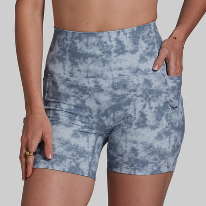 Blue tie-dye shorts worn by a person on a plain background