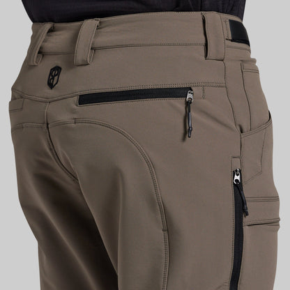 Close-up of the back waist and cargo pockets of storm grey outdoor pants, showing a black zipper, belt loops, and a small black logo patch.