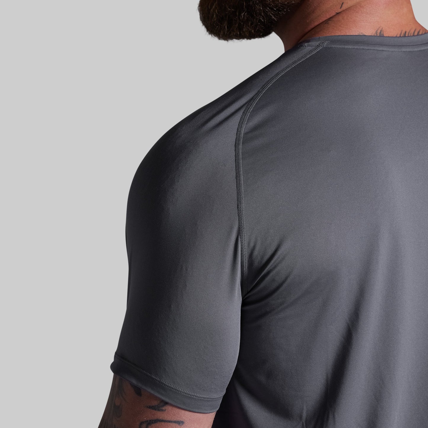 Gray athletic shirt worn by a person on a gray background