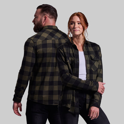 Two people wearing matching green and black plaid shirts against a plain background