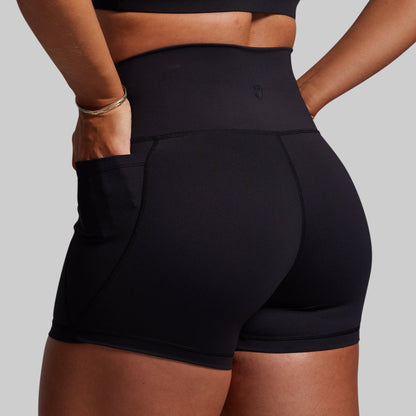 Black athletic shorts worn by a person on a gray background
