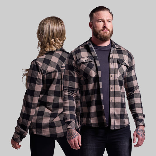Two people wearing matching plaid shirts against a plain background