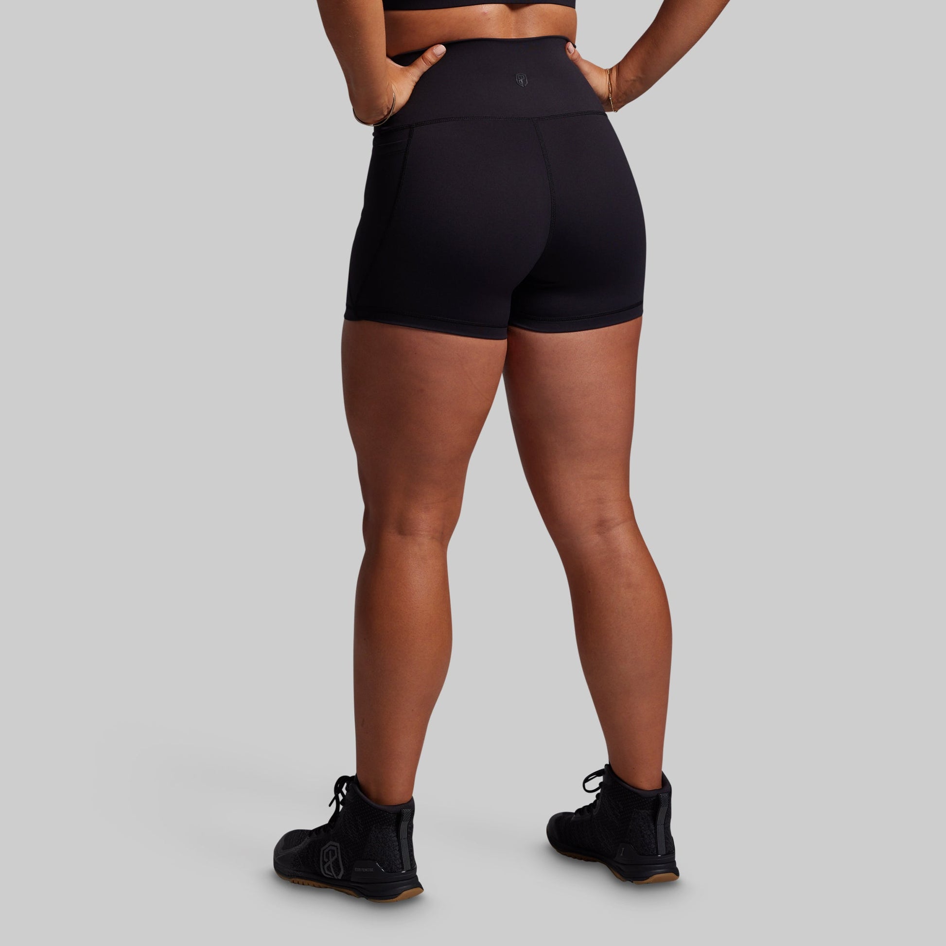 Person wearing black athletic shorts on a gray background