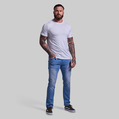 Man wearing a white t-shirt and blue jeans on a gray background