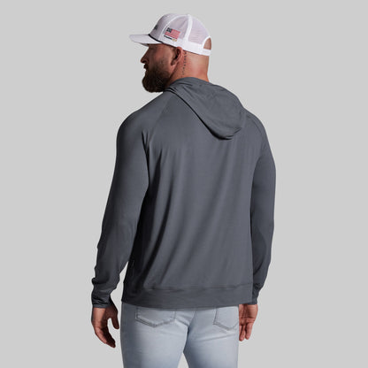 Man wearing a gray hoodie and light blue jeans on a gray background