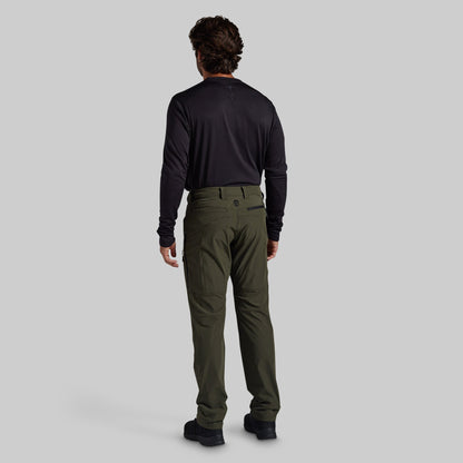 A man viewed from behind wearing a black long-sleeve shirt and olive green cargo pants against a solid gray background.