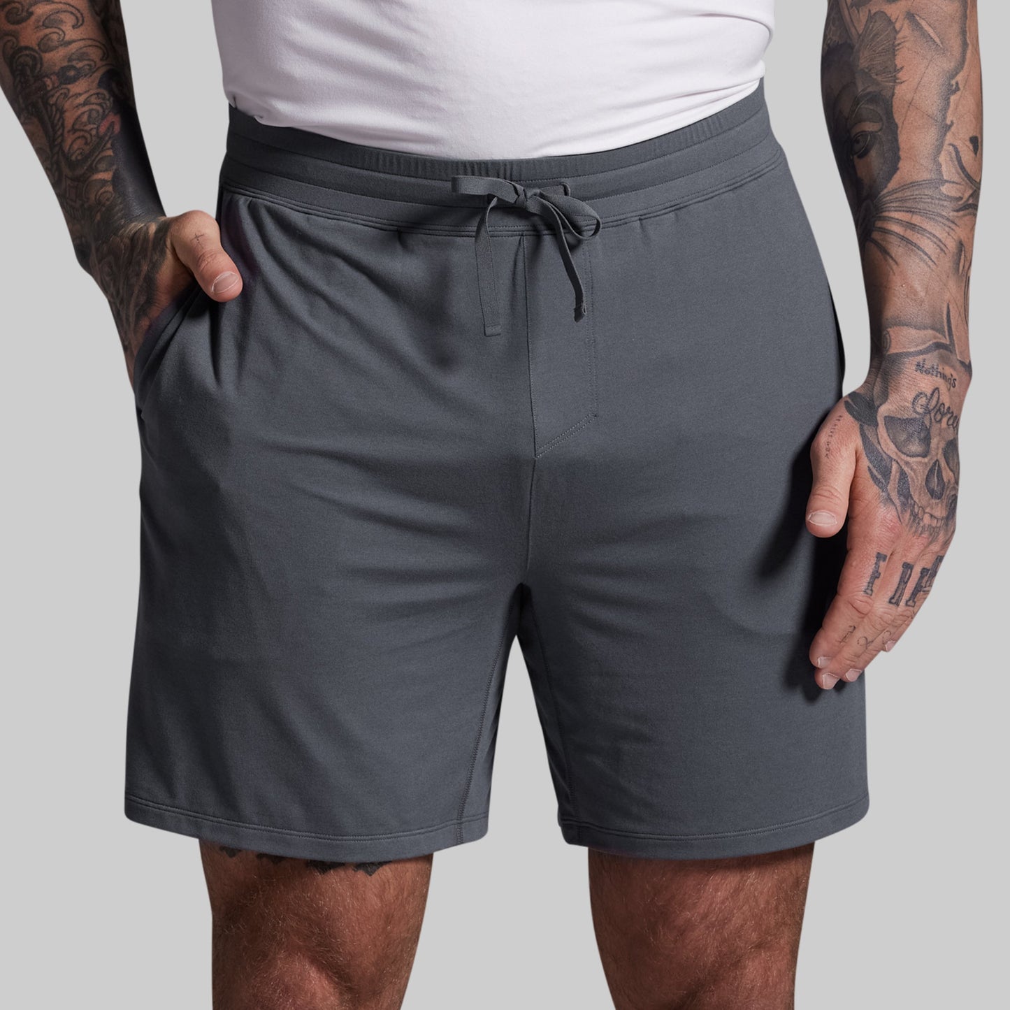 Person wearing gray shorts with a plain background