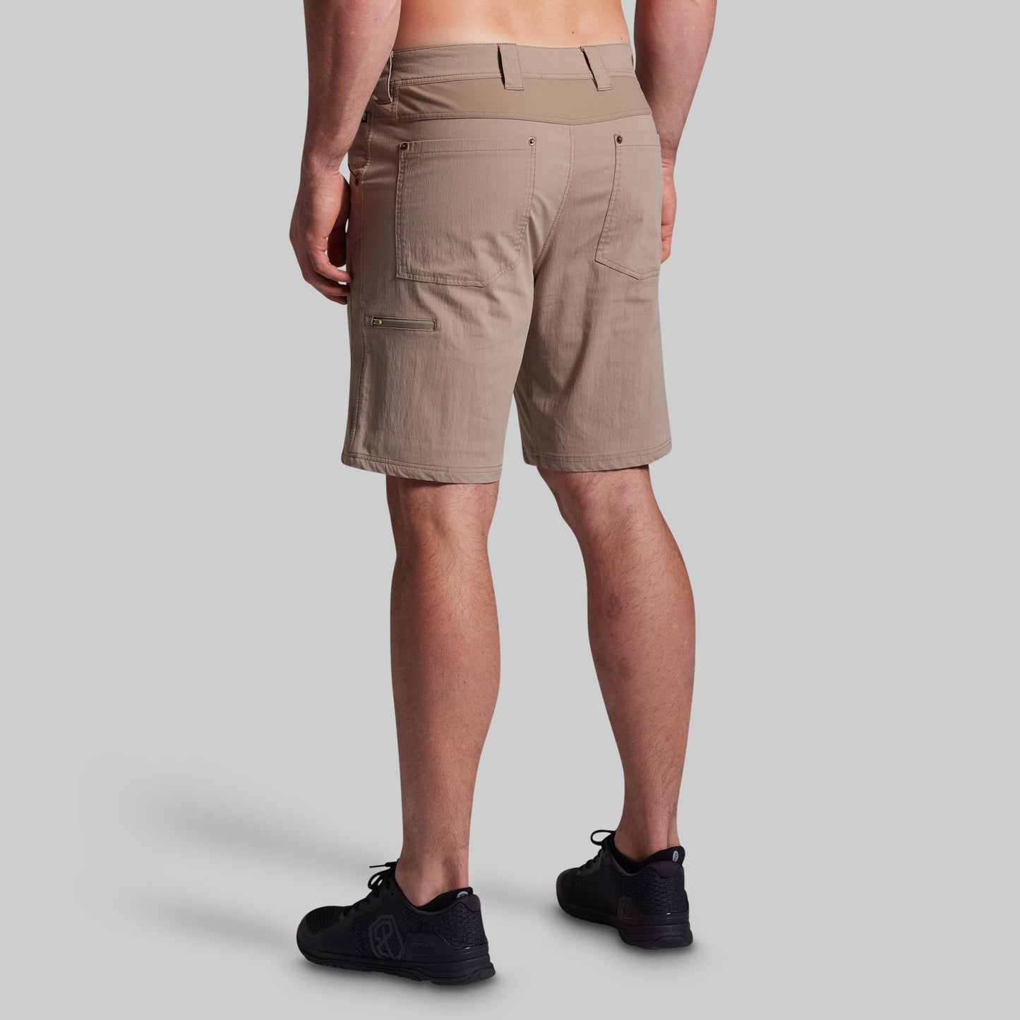Beige shorts worn by a person on a gray background